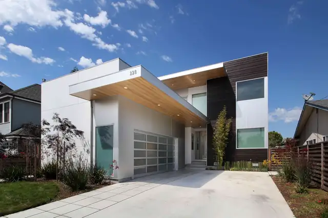 Modern white home with a wood-clad overhang, dark accent siding and a frosted glass garage door on the Westside of Santa Cruz