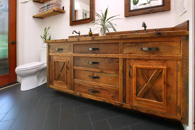 Rustic primary bath with a reclaimed wood double vanity, barn-style X doors and charcoal herringbone tile floor