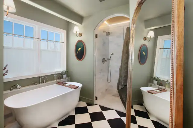 Classic bathroom with a freestanding tub, black and white checkerboard floor, sage walls and an arched marble shower