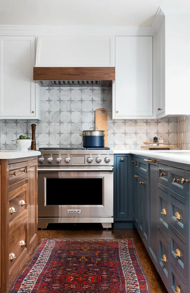 Classic navy and walnut kitchen with a pro range, patterned tile backsplash and wood range hood trim