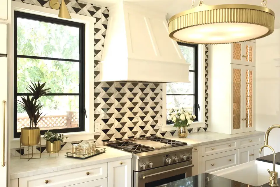 Kitchen remodeling Santa Cruz project with a black and white geometric tile backsplash, white custom range hood, brass drum light and black-framed windows