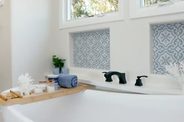 Seabright bathroom with a soaking tub, matte black tub faucet and blue patterned tile insets below the windows