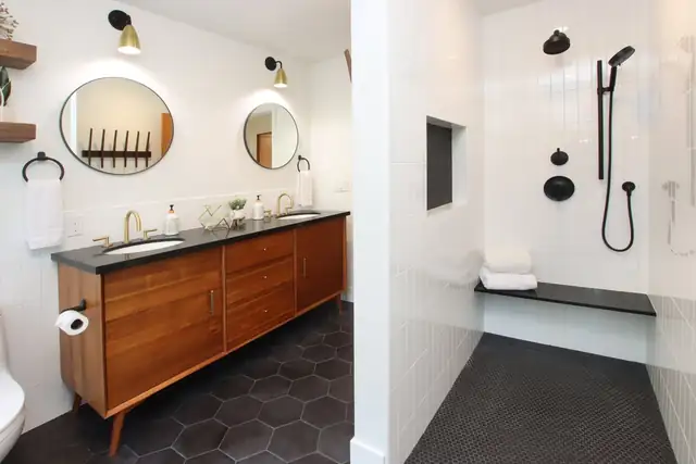 Pasatiempo bathroom remodel with a wood double vanity, black hex tile floor and curbless walk-in shower with a black granite bench