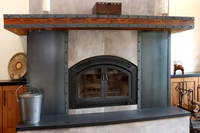 Santa Cruz Mountains home remodel with a riveted steel fireplace surround, arched firebox door and reclaimed wood mantel