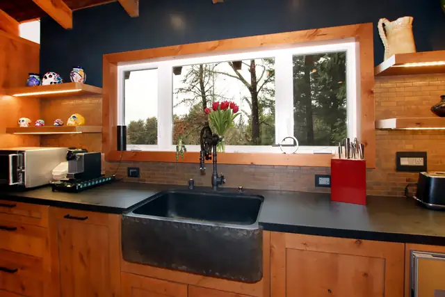 Santa Cruz Mountains kitchen with a hammered copper apron sink, knotty alder cabinets, open shelves and a wide window onto the trees